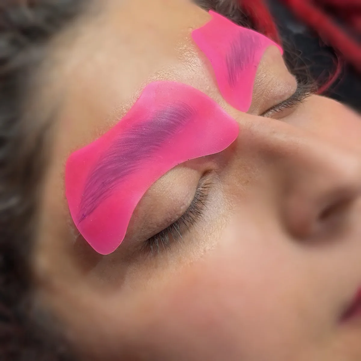 Cera rosa aplicada sobre la zona de ambas cejas durante el cuidado de su contorno